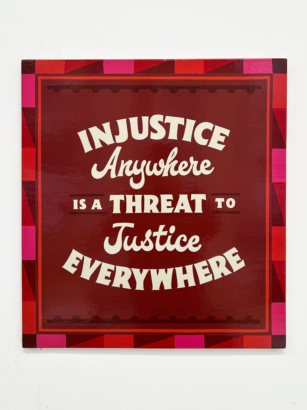 Red sign with white text 'Injustice anywhere is a threat to justice everywhere' on a white background